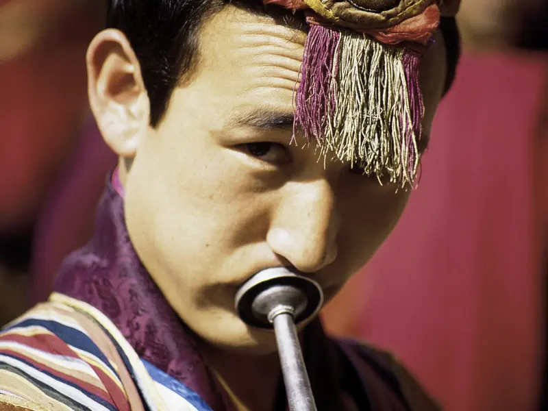 Unterwegs sehen wir auf unserer Rundreise viele Bhutaner in traditioneller Kleidung wie diesen Musiker.