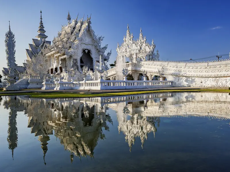 Lassen Sie sich auf Ihrer individuellen Rundreise durch Laos und Kambodscha vom schneeweißen Tempel Wat Rong Khun in Chiang Rai fazinieren! Spazieren Sie durch die Gänge und staunen Sie über die fantastische Architektur.