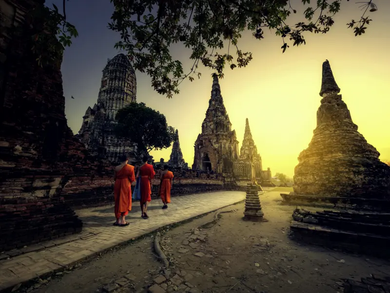 Mystisch sieht es aus, wenn die Mönche zum Sonnenaufgang durch die Tempelruinen der früheren Hauptstadt Ayutthaya marschieren.