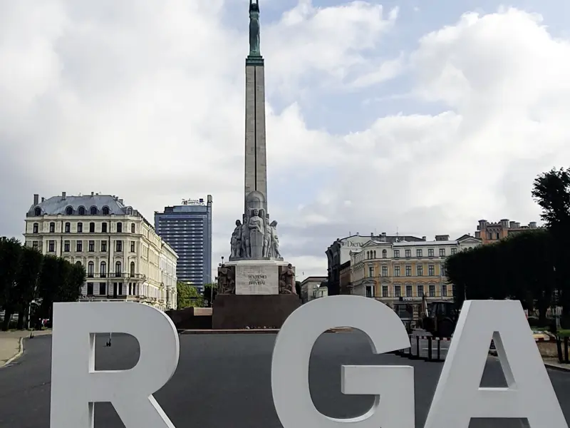 Auf unserer smart&small Reise durch das Baltikum posieren für ein perfektes Urlaubsfoto zwischen den großen Buchstaben der lettischen Hauptstadt Riga, im Hintergrund die Altstadt und das Friedensdenkmal.