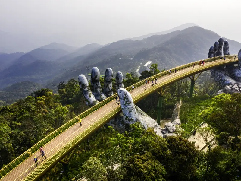 In den Bergen Zentralvietnams schreiten junge Traveller ab 35 gemeinsam über die spektakuläre Golden Bridge.