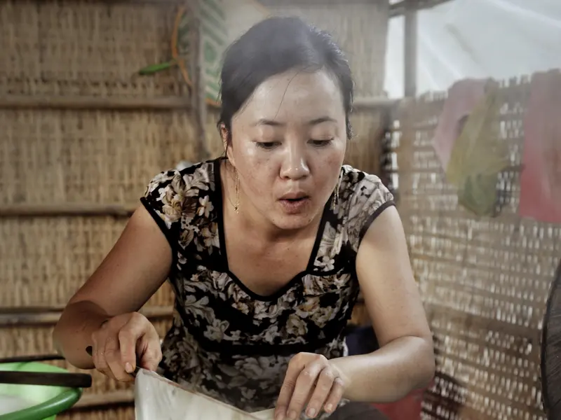 Eine Vietnamesin demonstriert Ihnen im Mekongdelta, wie auf traditionelle Art Reispapier für die Zubereitung von Frühlingsrollen hergestellt wird.