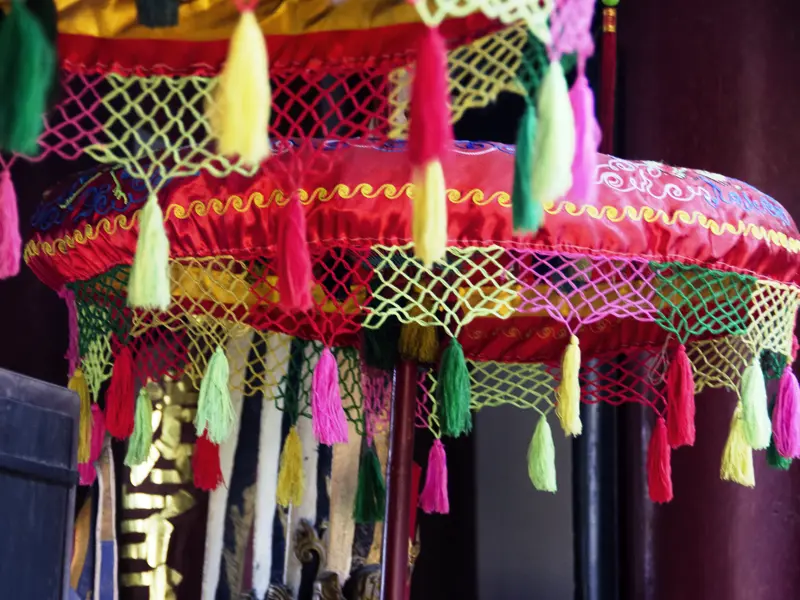 Auf Ihrer individuellen Rundreise durch Vietnam, Kambodscha und Laos sehen Sie in Hoi An bunte Schirme im Tempel.
