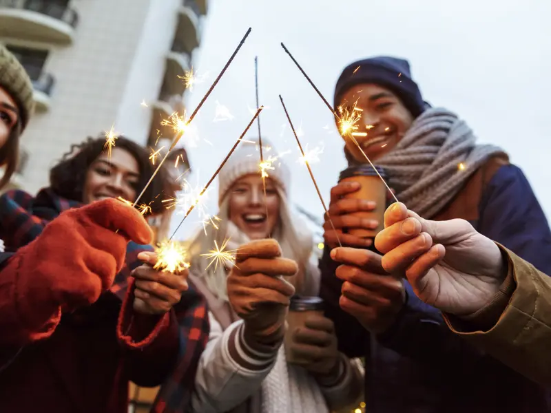 Eine Gruppe junger Reisender feiert mit Wunderkerzen Silvester in Helsinki