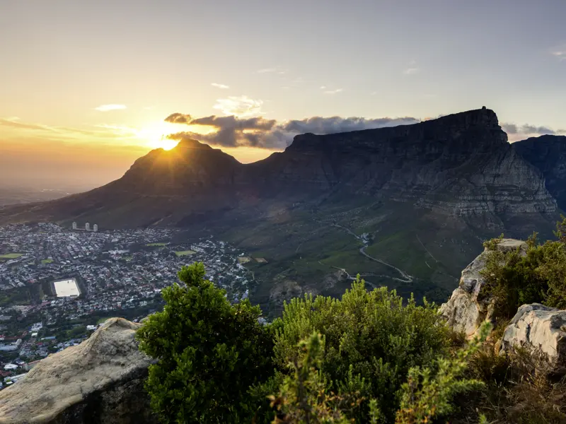 Wir blicken vom Signal Hill auf Kapstadt und den Tafelberg im Gegenlicht.