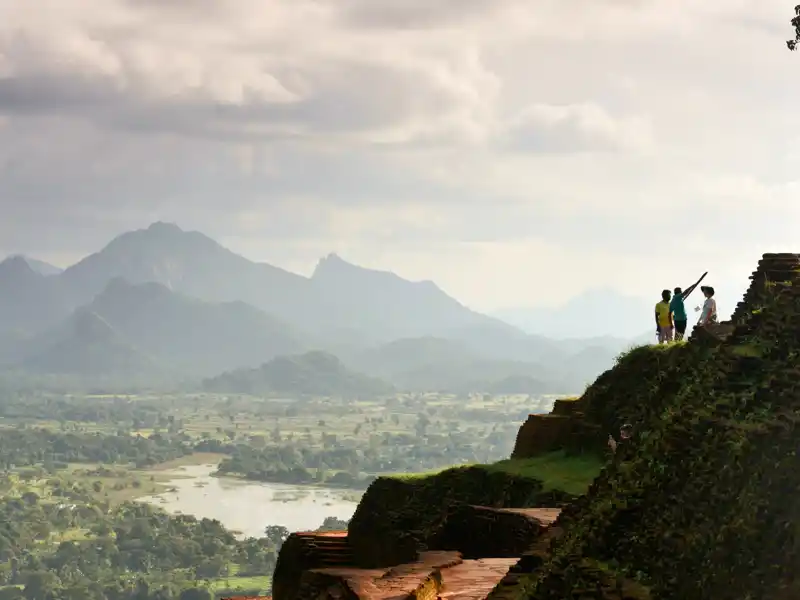 Erklimmen Sie über zahlreiche Stufen den Sigiriya Rock in Sri Lanka und genießen Sie die Aussicht auf die grüne Landschaft.