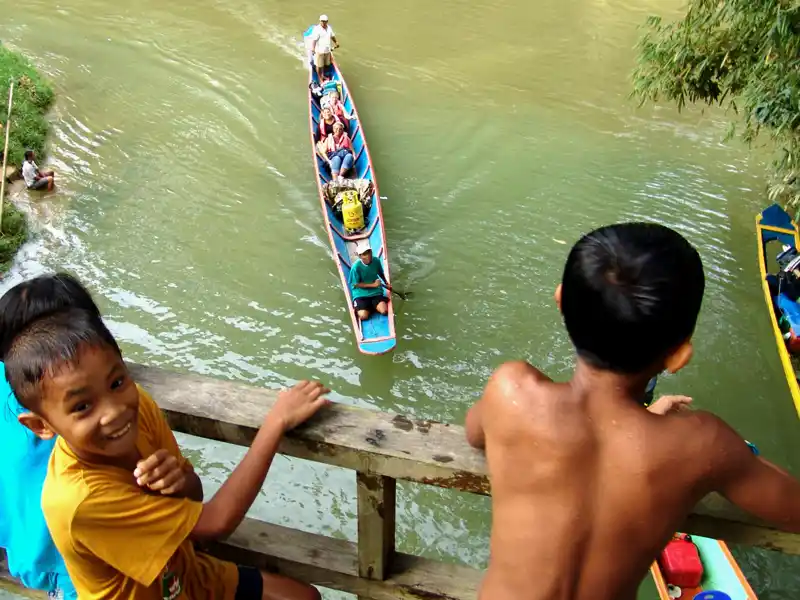 Spaß auf dem Wasser -  Kinder des Volkes Iban in Sarawak beim Baden und Begrüßen von Touristen.