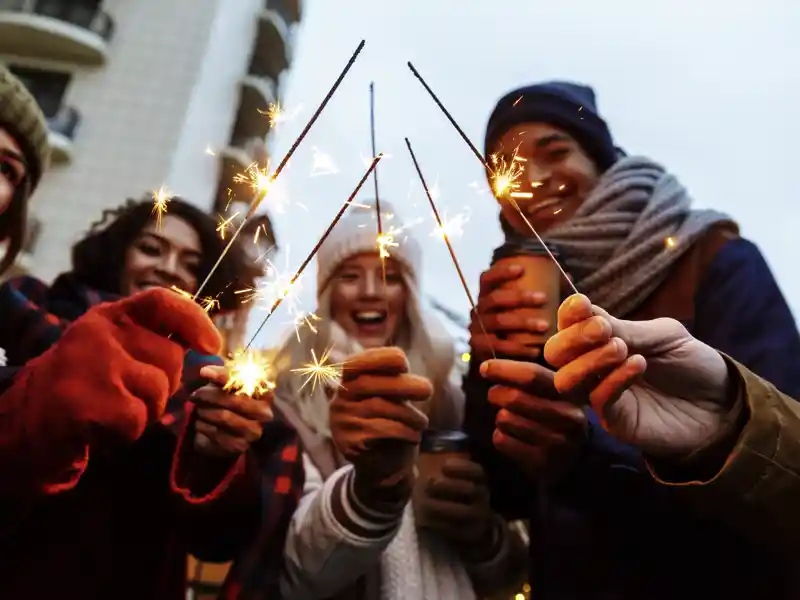 Eine Gruppe junger Reisender feiert mit Wunderkerzen Silvester in Helsinki