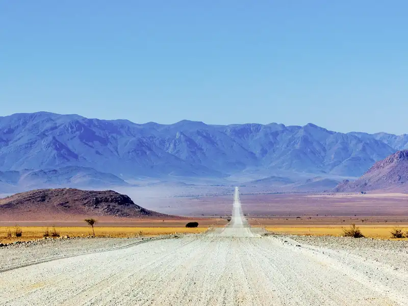 Eine Schotterpiste scheint schier endlos in den Weiten des namibianischen Landes zu verschwinden.